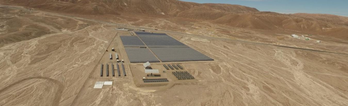 Aerial image of large rectangular array of solar panels in a desert.