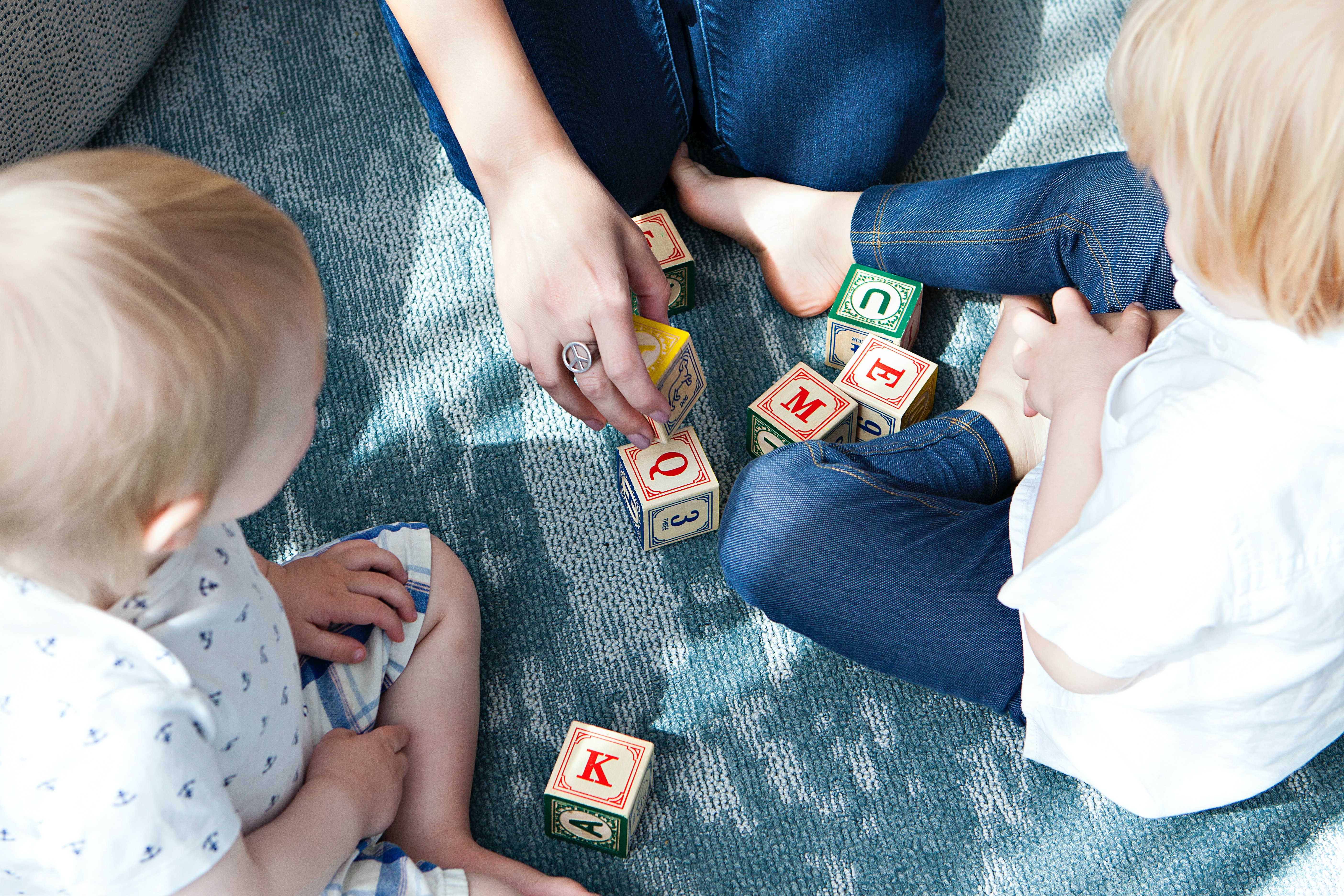 A nanny plays with blocks together with two children